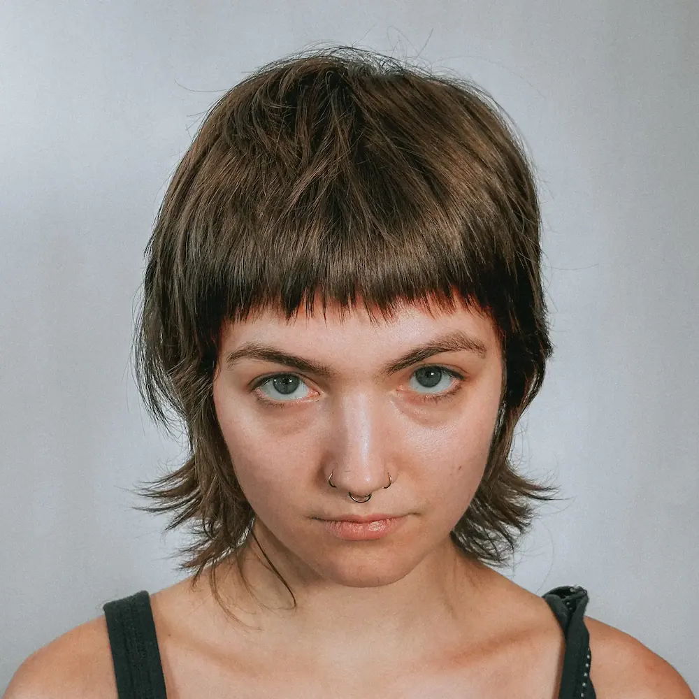 Low-maintenance women’s haircut featuring cropped bangs and layered ends